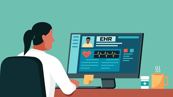 Female doctor using computer with electronic health record on screen